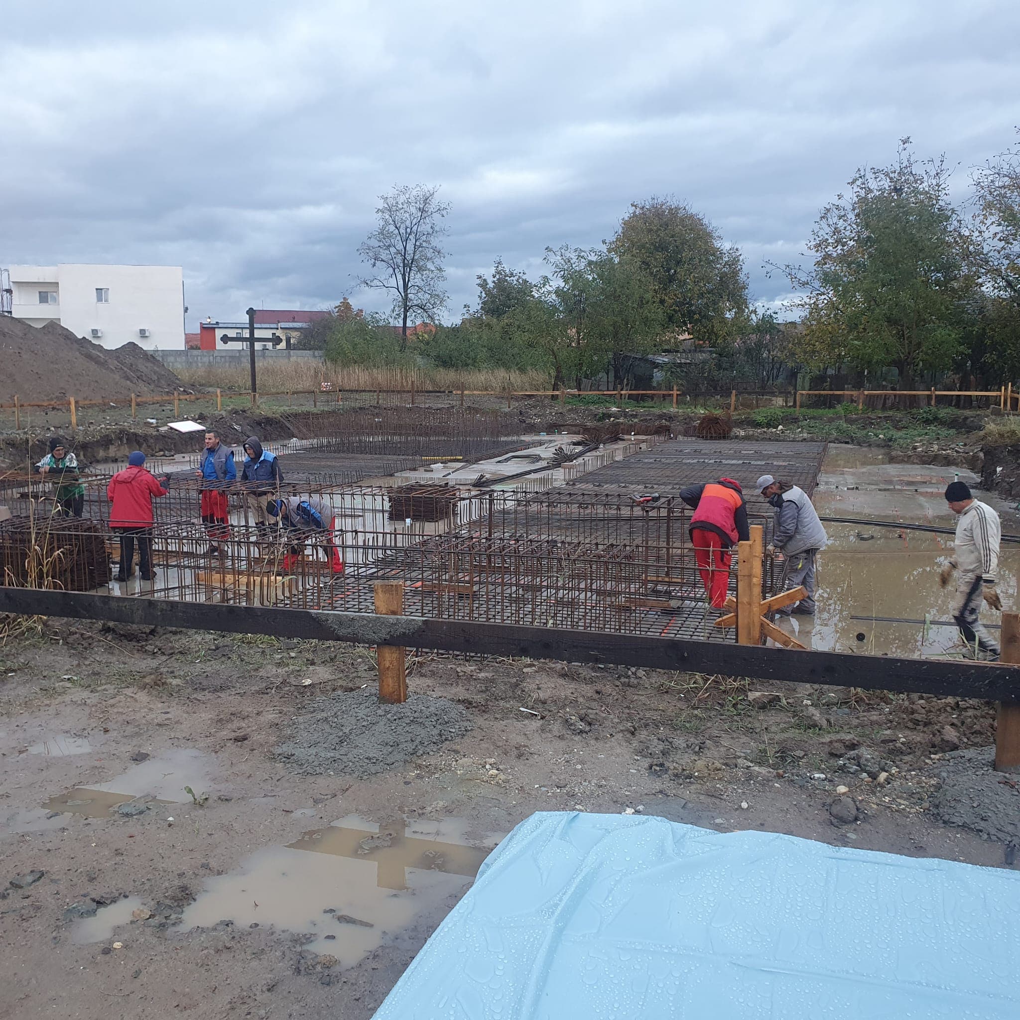 Muncitori turnând și nivelând betonul fundației